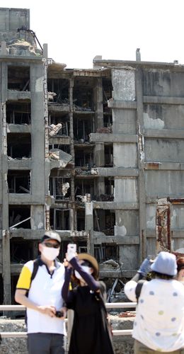 군함도 폐허 배경으로 기념사진(하시마=연합뉴스) 이세원 특파원 = 1일 오전 일본 나가사키현 하시마(일명 '군함도')에서 방문객이 일본 최초의 철근 콘크리트 아파트인 30호 건물을 배경으로 기념사진을 찍고 있다.