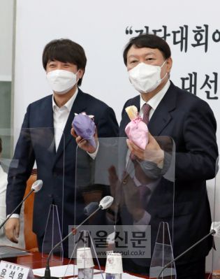 - 8일 서울 여의도 국회에서 열린 국민의힘 최고위원회의에 참석한 이준석 대표가 당 대선후보인 윤석열 후보에게 선거에 도움이 되는 복주머니를 전달하고 있다.2021. 11. 8 김명국 선임기자 daunso@seoul.co.kr