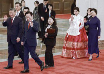 李在明总统夫妇和中国国家主席习近平夫妇5日在北京人民大会堂举行的正式欢迎仪式结束后向孩子们挥手致意/韩联社