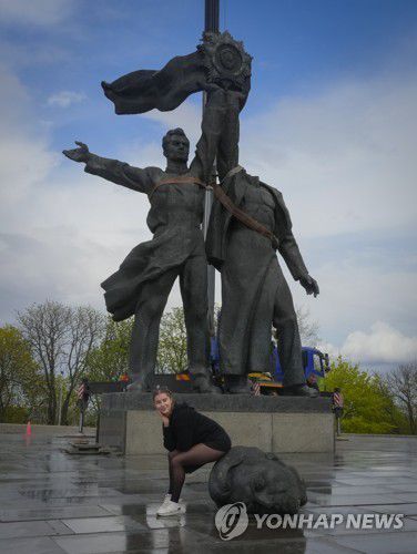 잘린 동상 머리 위에 앉아 기념촬영하는 키이우 시민(AP=연합뉴스) 우크라이나 키이우시가 소련 시절 제작돼 러시아와 우호관계를 상징해 온 동상을 철거했다고 로이터 통신 등이 26일(현지시간) 보도했다. 재판매 및 DB금지.