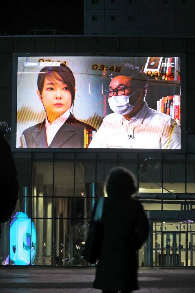 윤석열 국민의힘 대선후보의 배우자 김건희씨의 ‘7시간 전화통화” 내용이 MBC 시사프로그램 ‘스트레이트’를 통해 방송된 16일 한 시민이 서울 마포구 상암동 MBC사옥에 걸린 전광판을 통해 해당 방송을 보고 있다.   연합뉴스