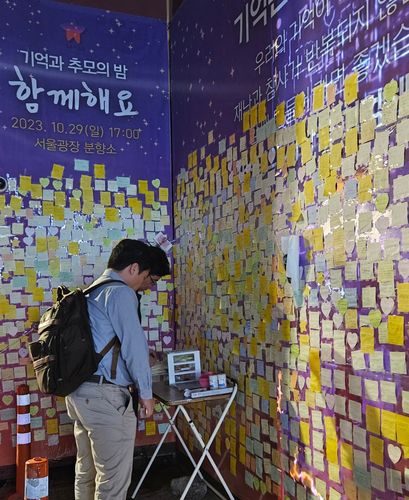 추모의 벽 앞에서 포스트잇에 글귀 쓰는 시민들[촬영 정윤주]