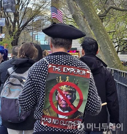도널드 트럼프 미국 대통령의 정책을 반대하는 시민들이 지난 19일 미국 뉴욕 맨해튼에서 시위를 벌이고 있다. 시위 참가자가 등에 맨 팻말에 '트럼프는 벌거벗은 임금님'이라는 문구가 보인다. /사진=심재현 특파원