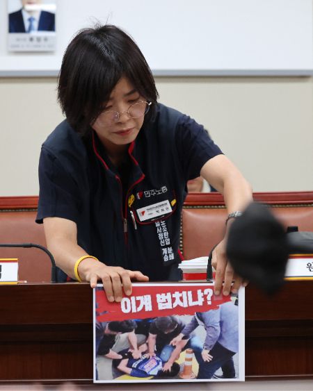 노동자위원인 민주노총 박희은 부위원장이 경찰의 과잉 진압을 규탄하는 손팻말을 붙이고 있다. 연합뉴스