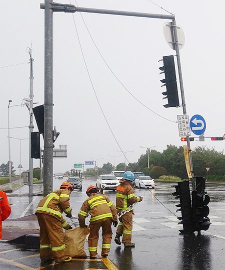 26일 오전 제8호 태풍 ‘바비(BAVI)’로 인한 강풍으로 제주 제주시 연동 마리나호텔 인근 사거리에 있는 신호등이 90도로 꺾인 채 도로에 쓰러져 있다. 소방대원들이 긴급 출동해 안전 조치를 하고 있다. 제주=뉴시스
