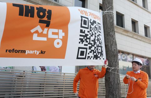 개혁신당 이준석 대표 등이 26일 국회의사당 앞 가로수에 정당 정책 홍보 현수막을 걸고 있다. (사진=연합뉴스 제공)