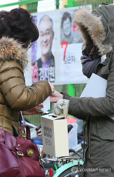 <2012대선> '지금은 출구조사 중' (서울=연합뉴스) 한종찬 기자 = 18대 대통령선거일인 19일 서울 잠실본동 주민센터에 마련된 투표소 앞에서 출구 조사원들이 투표를 마치고 나오는 시민에게 출구조사를 하고 있다. 2012.12.19 saba@yna.co.kr