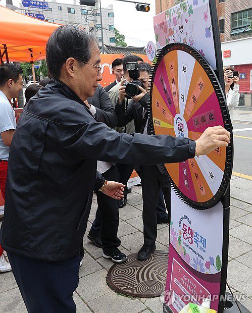 통인시장 사은행사 참가한 한덕수 총리(서울=연합뉴스) 최재구 기자 = 한덕수 국무총리가 20일 서울 종로구 통인시장을 방문해 상인들을 격려하고 구매 영수증으로 사은행사에 참여하고 있다. 2024.5.20
