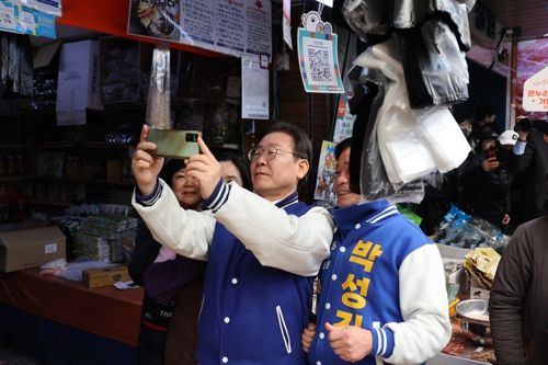 15일 오전 울산 남구 수암시장을 방문한 이재명 더불어민주당 대표(가운데)가 시장 상인과 사진을 찍고 있다. 오른쪽은 울산 남구을 민주당 박성진 후보. 연합뉴스
