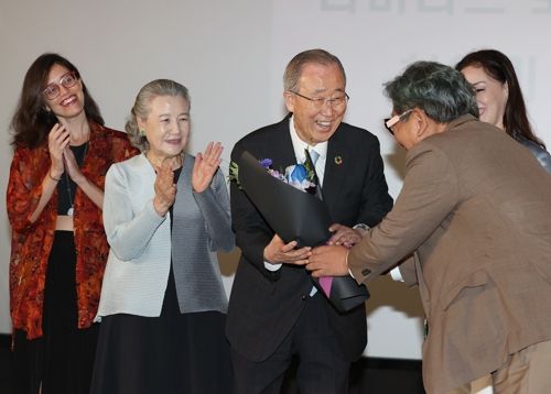 반기문 전 유엔 사무총장이 19일 서울 용산구 CGV 아이파크몰점에서 열린 다큐 영화 <조용한 리더> 시사회에서 한 참석자에게 꽃다발을 받고 있다. 연합뉴스