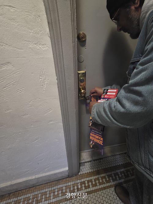 홀리가 조란 맘다니 뉴욕시장 후보의 정책 홍보물을 현관 손잡이에 걸어두고 있다.  뉴욕 | 정유진 특파원