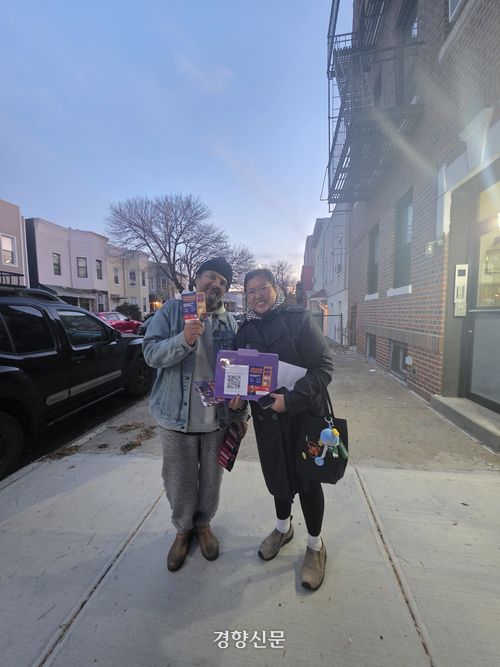 어느덧 날이 어둑어둑해진 가운데 홀리와 크리스티나가 조란 맘다니의 정책 홍보물을 들어 보이고 있다.   뉴욕 | 정유진 특파원