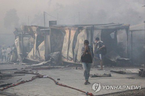 불에 탄 '모리아'에서 걸어 나오는 난민들의 모습[AFP=연합뉴스]