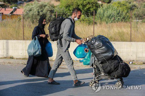 그리스 당국이 마련한 임시 수용시설 주변 도로를 걷는 모리아 캠프 체류자들. 2020.9.17. [AFP=연합뉴스]