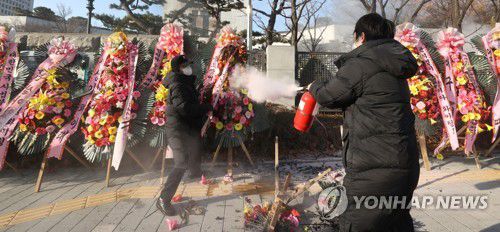 대검 앞 방화(서울=연합뉴스) 류영석 기자 = 5일 오전 서울 서초구 대검찰청 앞에서 한 남성이 윤석열 검찰총장 응원화환에 불을 붙이자 대검 보안요원들이 달려와 불을 끄고 있다. 2021.1.5 ondol@yna.co.kr