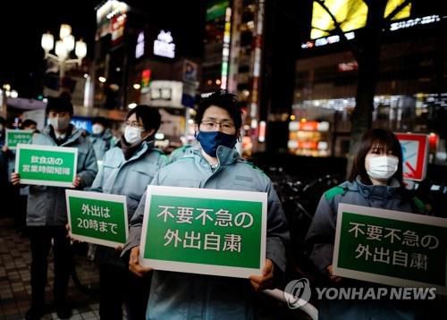(도쿄 로이터=연합뉴스) 일본 수도권 일부 지역에 신종 코로나바이러스 감염증(코로나19) 긴급사태가 발효한 8일 오후 도쿄도 직원이 외출자제, 음식점 영업시간 단축 등의 메시지가 적힌 안내판을 들고 신주쿠(新宿)구의 유흥가를 돌고 있다.