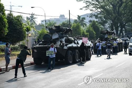 15일 오전 쿠데타 항의 시위대가 길가의 장갑차 옆에서 사진을 찍고 있다.[AFP=연합뉴스]
