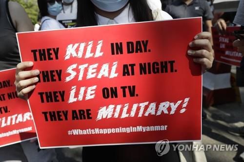 '군부는 낮에는 죽이고, 밤에는 훔치고, TV에선 거짓말한다'고 적힌 손팻말.[EPA=연합뉴스]