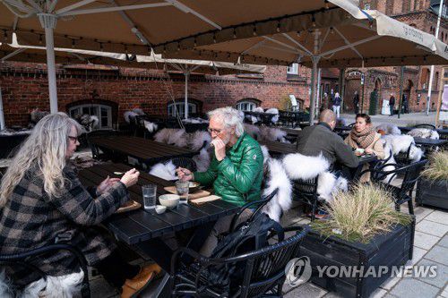 지난 21일(현지시간) 식당, 카페, 술집이 다시 문을 연 가운데 덴마크의 한 야외 좌석에서 사람들이 앉아있다.[Claus Bech/Ritzau Scanpix/via REUTERS=연합뉴스. 재판매 및 DB 금지]