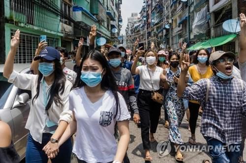 (양곤 AFP=연합뉴스) 미얀마 최대 도시 양곤에서 지난달 27일(현지시간) 군부 쿠데타에 항의하는 시위대가 저항의 표시로 세 손가락 경례를 하며 거리를 지나고 있다.