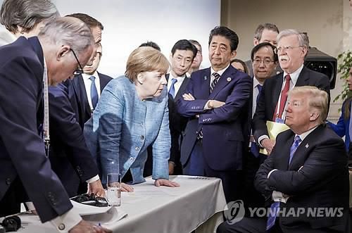 2018년 G7 정상회의 때 팔짱 낀 트럼프와 탁자 누른 메르켈 [연합뉴스 자료사진]