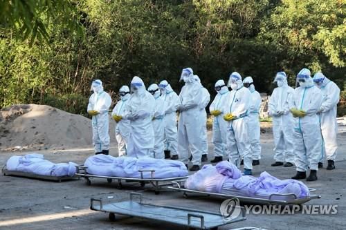 만달레이의 코로나19 사망자 시신 앞에서 개인보호장비(PPE)를 입은 자원봉사자들이 기도하고 있다.(자료사진) [로이터=연합뉴스]