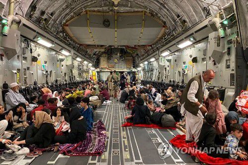 19일(현지시간) 아프가니스탄인들이 카불 국제공항에서 외국으로 탈출하기 위해 미군 수송기 안에 앉아있는 모습. [AFP=연합뉴스]