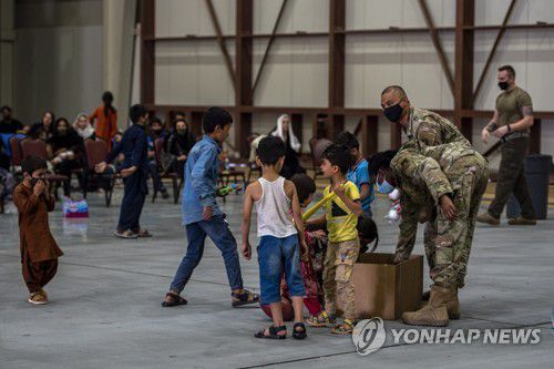 지난 16일 카타르 도하 알우데이드 기지에서 미군 장병들이 아프간 어린이들에게 장난감을 나눠주고 있다. [미 공군/UPI=연합뉴스 자료사진]