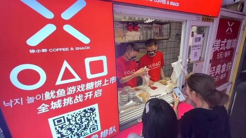 중국에 등장한 '오징어게임' 달고나 가게(상하이=연합뉴스) 차대운 특파원 = 지난 12일 중국 상하이 인민광장 인근에 있는 한국식 설탕 과자 '달고나' 가게에서 손님들이 줄을 서 물건을 받기를 기다리고 있다. 2021.10.15. [연합뉴스 자료사진] photo@yna.co.kr