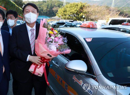 꽃다발 든 윤석열(부산=연합뉴스) 손형주 기자 = 국민의힘 윤석열 대선 경선 후보가 19일 부산 연제구 부산개인택시조합에 택시를 타고 도착해 관계자로부터 꽃다발을 받고 있다. 2021.10.19 handbrother@yna.co.kr