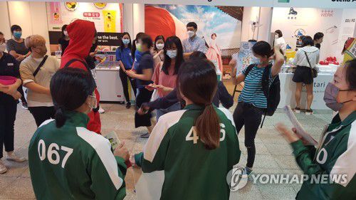 '오징어게임'의 병정과 참가자 분장을 한 스태프(홍콩=연합뉴스) 윤고은 특파원 = 지난 29일 홍콩에서 시작한 한국문화 종합체험 행사 '한국광장 2021'에 등장한 '오징어 게임'의 '참가자'들. pretty@yna.co.kr