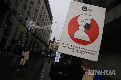 (브뤼셀 신화=연합뉴스) 2일(현지시간) 벨기에 브뤼셀에 있는 코로나19 예방 마스크 착용 표지판 옆을 사람들이 걸어가고 있다. 2021.12.3. photo@yna.co.kr