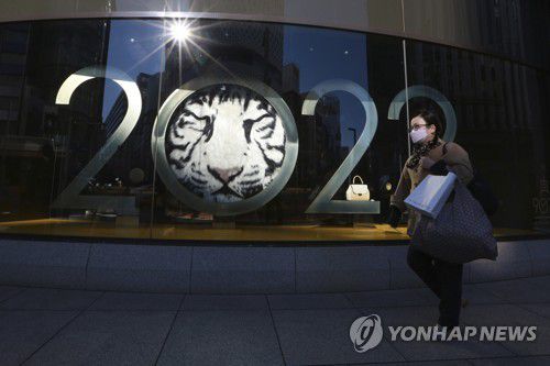 도쿄의 새해 장식물 앞을 마스크를 쓰고 지나가는 여성. 2021.12.30[AP=연합뉴스]