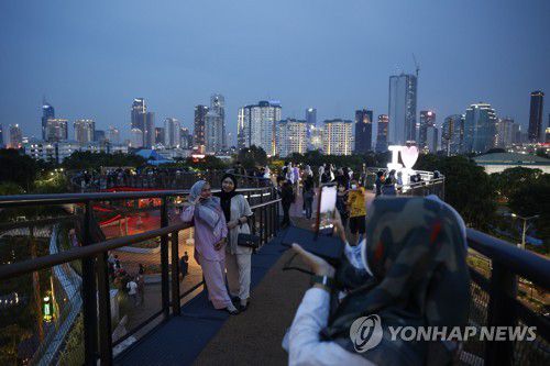 자카르타 도심을 배경으로 사진찍는 사람들. 2021.12.29[EPA=연합뉴스]