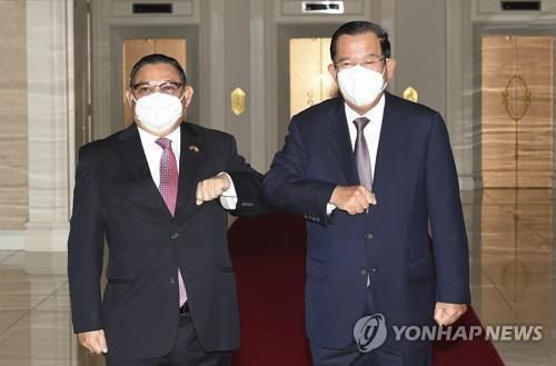 팔꿈치 인사하는 미얀마 군정 외교장관(왼쪽)과 훈센 캄보디아 총리. 2021.12.7캄보디아를 찾은 미얀마 군정의 운나 마웅 르윈 외교장관(왼쪽)이 훈센 캄보디아 총리와 팔꿈치 인사를 하고 있다. 2021.12.7 [캄보디아 국영TV 제공/AP=연합뉴스. 재판매 및 DB 금지]