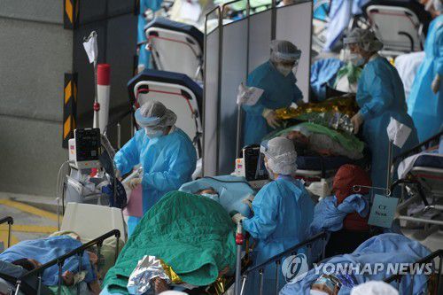 (로이터=연합뉴스) 17일 홍콩의 한 병원 바깥에서 대기 중인 코로나19 환자들을 의료진이 돌보는 모습.