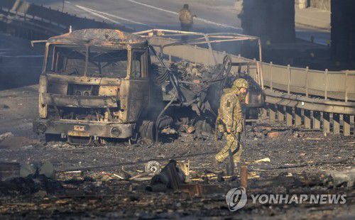 키예프에 불탄 군용 트럭(키예프 AP=연합뉴스) 26일(현지시간) 우크라이나 키예프 거리에서 불탄 군용 트럭 잔해 앞으로 우크라이나군인이 지나고 있다. 2022.2.26 photo@yna.co.kr