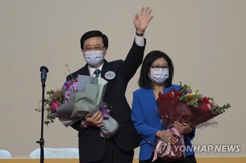 홍콩 새 행정장관에 당선된 존 리(홍콩 AP=연합뉴스) 8일 홍콩 행정장관 선거에서 단독 출마해 당선된 존 리(왼쪽) 전 정무 부총리가 부인과 함께 단상에 올라 손을 흔들고 있다. 홍콩 컨벤션센터에서 선거위원회의 간접 선거로 진행된 이날 선거에서 리 후보는 역대 최다인 94%의 지지로 당선됐다. 2022.5.8 leekm@yna.co.kr