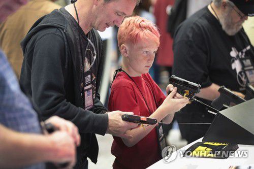 지난 2019년 4월 미국 인디애나주에서 열린 전미총기협회(NRA) 연례회의·전시회에서 11살짜리 아들과 총기를 살펴보는 남성 [AFP 연합뉴스 자료사진. 재배포 및 DB 금지]