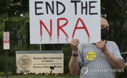 "전미총기협회(NRA)를 끝내라"(페어팩스[미 버지니아] AFP=연합뉴스) 25일(현지시간) 미국 총기 규제론자들이 버지니아주 페어팩스에 있는 전미총기협회(NRA) 사무실 밖에서 텍사스주 총격사건 희생자들을 추모하는 촛불집회를 열고 있다. 한 참가자가 "NRA를 끝내라"라고 쓴 푯말을 들고 있다. 2022.5.26 photo@yna.co.kr