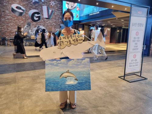 '이상한 변호사 우영우' 마지막 회 단체관람 행사(서울=연합뉴스) 강애란 기자 = 김나희(44)씨가 18일 오후 서울 용산구 한강로동 CGV용산점에서 열린 드라마 '이상한 변호사 우영우' 마지막 회 단체관람 행사에서 롯데월드 측에 돌고래 벨루가 방류 시위를 하고 있다. 2022.8.18