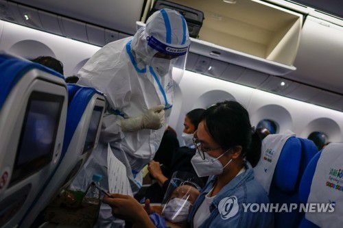 필리핀 마닐라 공항에서 이륙을 앞둔 중국 항공사 기내에서 한 직원이 방역복을 입고 승객들을 돕고 있다. [EPA=연합뉴스] ※ 기사와 직접 관련이 없습니다.