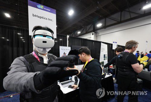 CES 2023 사전 공개 행사(라스베이거스=연합뉴스) 홍해인 기자 = 세계 최대 가전·IT(정보기술) 박람회 CES 2023 개막에 앞서 3일 오후(현지시간) 미국 네바다주 라스베이거스 만달리나 베이 컨벤션 센터에서 열린 'CES 2023 사전 공개(UNVEILED)' 행사에서 각국 미디어 관계자들이 국내 기업인 비햅틱스(bHaptics)가 진동으로 촉감을 전달하는 '택트글러브'와 '택트수트'를 체험해 보고 있다. 이 장갑을 끼고 조끼를 입은 뒤 가상세계에 접속해 광선검을 휘두르면 맞은 상대방은 충격을 느낄 수 있다. 2023.1.4 hihong@yna.co.kr