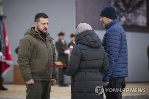 전사자 유족에 훈장 전하는 젤렌스키 대통령(키이우 AP=연합뉴스) 볼로디미르 젤렌스키 우크라이나 대통령(왼쪽)이 24일(현지시간) 러시아의 우크라이나 침공 1년을 맞아 수도 키이우에서 열린 행사에서 전투 중 숨진 병사의 유족에 훈장을 전달하고 있다. [우크라이나 대통령실 제공] 2023.02.24 ddy04002@yna.co.kr