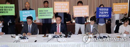 복지부 장관과 팻말(서울=연합뉴스) 한상균 기자 = 조규홍 보건복지부 장관이 7일 중구 프레지던트 호텔에서 열린 국민연금기금운용위원회에 참석하고 있다. 그 뒤에 기금 개악에 반대하는 공적연금강화국민행동 회원들이 팻말을 들고 있다. 2023.3.7 xyz@yna.co.kr