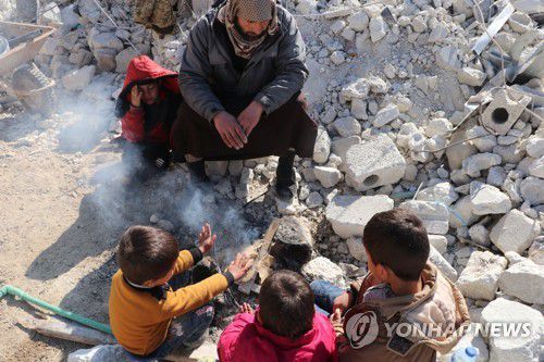 대지진으로 폐허가 된 시리아 도시 속 가족(서울=연합뉴스) 대지진으로 폐허가 된 시리아의 한 도시에서 가족으로 보이는 어른과 아이들이 불을 피워 추위를 피하고 있다. [월드비전 제공]