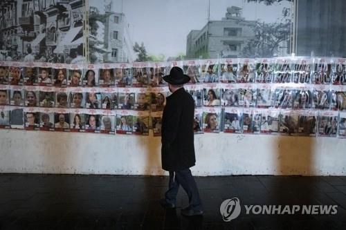 예루살렘서 이스라엘인 인질 사진 보는 남성(예루살렘 신화=연합뉴스) 27일(현지시간) 이스라엘 예루살렘에서 한 남성이 가자지구에 잡혀있는 인질들의 사진을 보고 있다. 팔레스타인 무장정파 하마스는 일시 휴전 첫날인 지난 24일부터 이날까지 이스라엘 인질 총 50명을 풀어줬다. 2023.11.28 danh2023@yna.co.kr