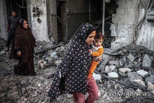 어린아이 데리고 공습 대피하는 가자 주민(라파 AFP=연합뉴스) 23일(현지시간) 가자지구 남부 라파에서 한 주민이 이스라엘군의 공습을 피해 아이를 데리고 대피하고 있다. 캐서린 러셀 유엔아동기금(UNICEF·유니세프) 총재는 이날 가자지구에 대해 "어린이가 살기에 전 세계에서 가장 위험한 곳"이라고 말했다. 2023.11.23 danh2023@yna.co.kr