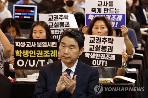 지난 8월 10일 오전 서울 코리아나호텔에서 열린 ‘교권 회복 및 보호를 위한 교육부-국가교육위원회 공동주최 토론회’에서 서울교육사랑학부모연합 등 단체가 학생인권조례 폐지를 촉구하는 피켓을 들고 있다. 앞은 이주호 부총리 겸 교육부 장관. [연합뉴스 자료사진. 재판매 및 DB 금지]