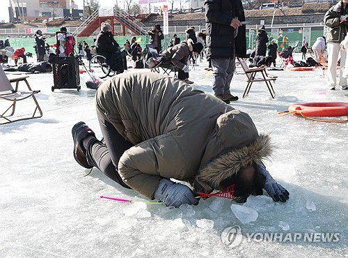 '산천어야 어디 있니'(화천=연합뉴스) 강태현 기자 = 13일 오전 강원 화천군 화천읍 화천천에서 열린 '2024 산천어축제' 얼음 낚시터에서 관광객이 얼음 구멍에 얼굴을 들이밀고 있다. 2024.1.14 taetae@yna.co.kr